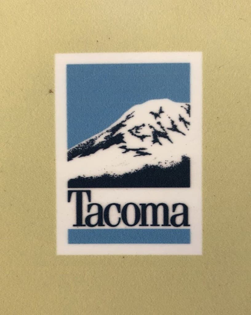 A Tacoma sticker with a mountain illustration and a serif wordmark