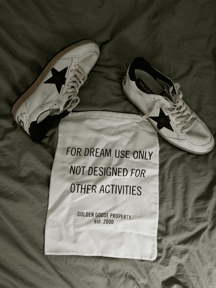 Golden Goose sneakers resting on a dust bag that reads For dream use only