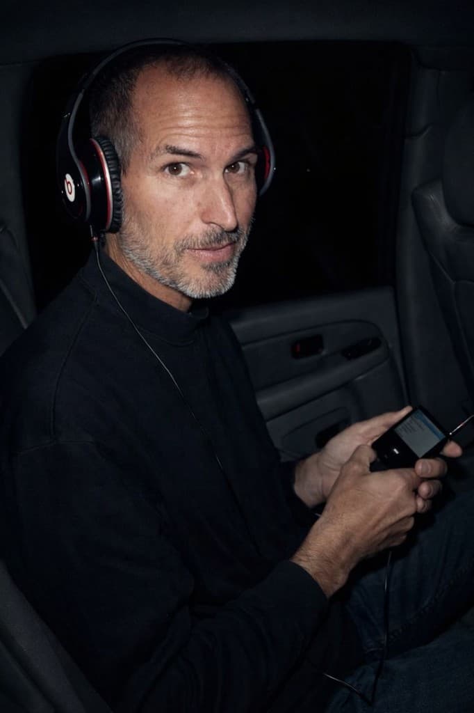 Steve Jobs in a car, wearing headphones and holding an iPod